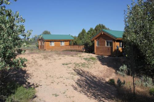 a couple of wooden cabins in a field with trees at Sevier River Ranch & Cattle Company in Hatch