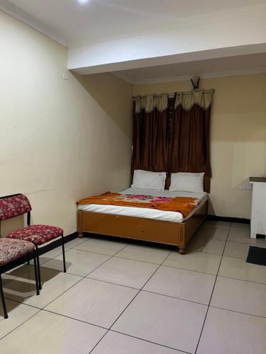 a bedroom with a bed and a window and a chair at EZHIL Residency in Kodaikānāl