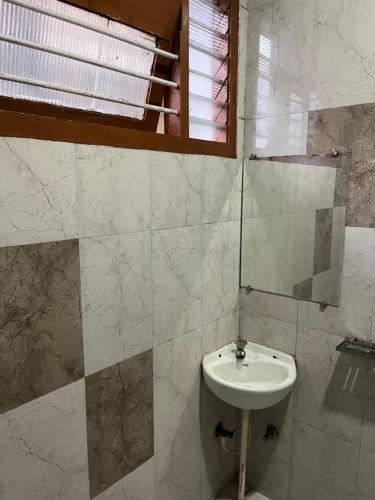 a bathroom with a sink and a mirror at EZHIL Residency in Kodaikānāl