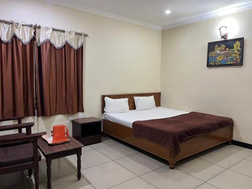 a hotel room with a bed and a desk and a bed sidx sidx sidx at EZHIL Residency in Kodaikānāl
