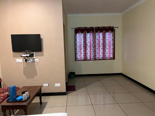 a living room with a tv and a couch and a table at EZHIL Residency in Kodaikānāl