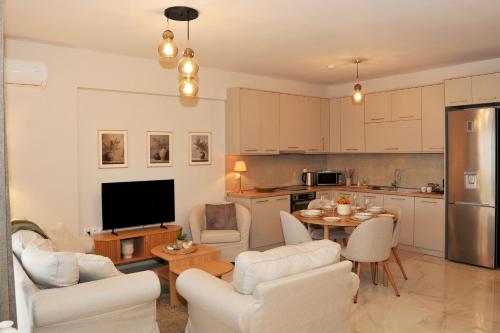 a living room with white furniture and a kitchen at Meteora Guest Houses in Kalabaka