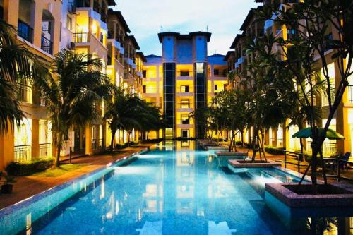 a large swimming pool with palm trees and buildings at Desaru Beach Luxury Suites Pool View 3Pax E1 in Bandar Penawar