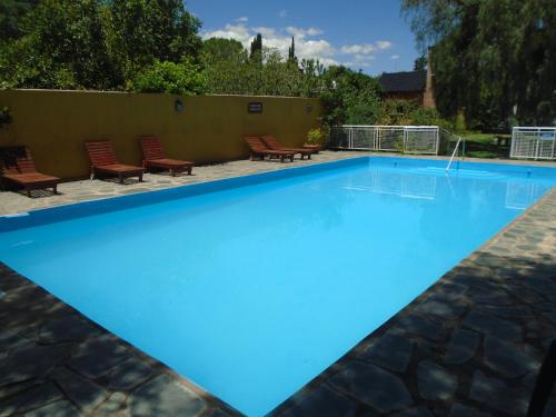 a large blue swimming pool with chairs around it at Hostería de los Césares in Merlo