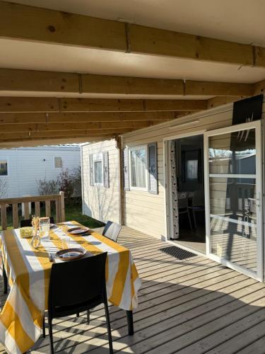 a table with a yellow and white table cloth on a deck at Camping de la Loire in Cordemais