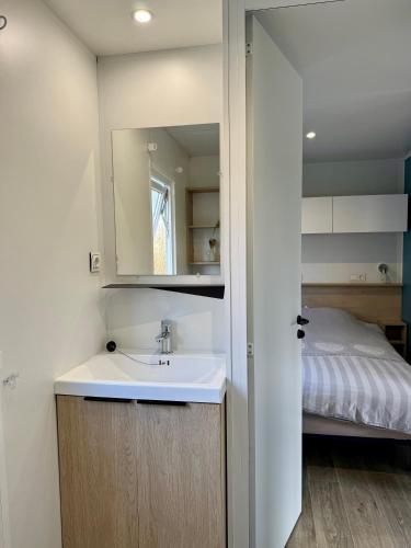 a bathroom with a sink and a bed at Camping de la Loire in Cordemais