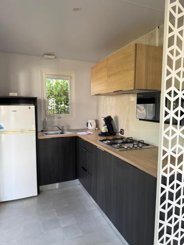 a kitchen with a white refrigerator and wooden cabinets at Camping de la Loire in Cordemais