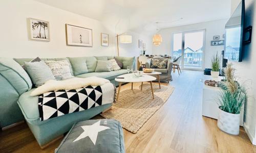 a living room with a green couch and a table at Surfbude, Olpenitz - moderne Ferienwohnung in direkter Strandnähe mit eigenem Eingang, Sauna, Kaminofen, Balkonterrasse und Parkplatz in Kappeln