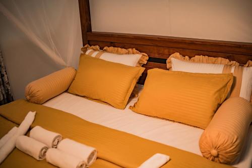 a bed with yellow pillows in a room at Royal Crest Villa in Batawala