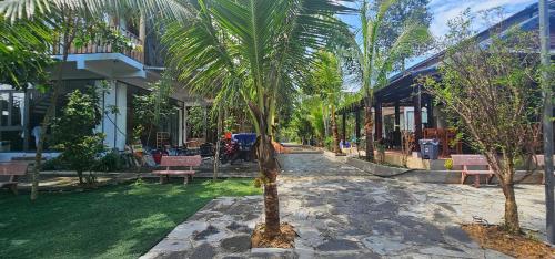 a palm tree in front of a building with benches at Coco Retreat in Tân Phú
