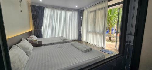 a bedroom with two beds and a large window at Coco Retreat in Tân Phú