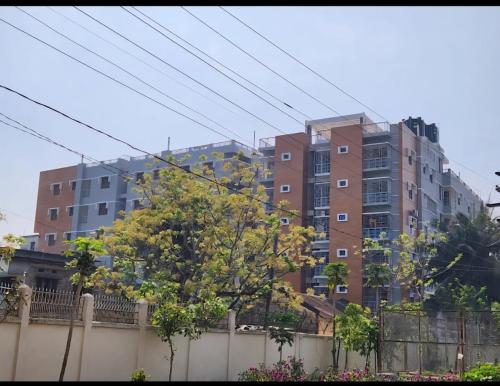 a tall apartment building in front of a fence at Enjoy Your Time in Jessore
