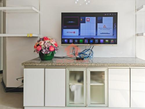a tv on top of a counter with a vase of flowers at Large & Strategic 3BR Taman Rasuna Apt Pool in Jakarta