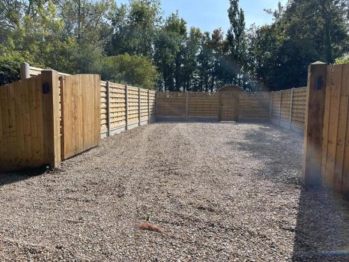 a wooden fence with a gate in a yard at Highgate Cabin in Takeley
