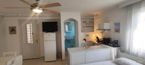 a kitchen with a ceiling fan and a white kitchen at Dandelion Paros Apartments I-II in Kóstos