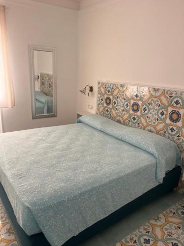 a bedroom with a bed with a headboard and a mirror at Vincanto Maiori Costiera Amalfitana in Maiori