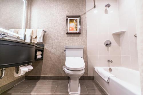 La salle de bains est pourvue de toilettes, d'une baignoire et d'un lavabo. dans l'établissement APA Hotel Woodbridge, à Iselin