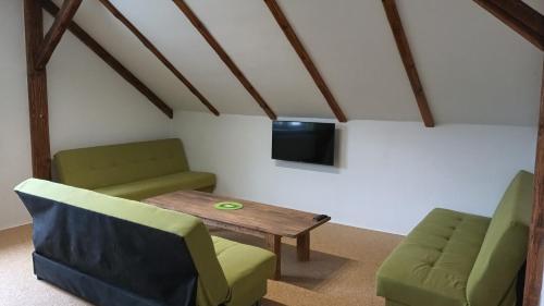 a living room with two chairs and a table and a tv at Penzion Zelená zahrada in Kladenské Rovné