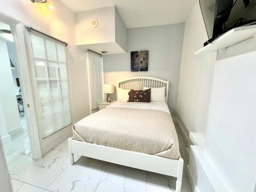 a white bedroom with a bed and a tv at Family Stay Ocean Reserve Resort Sunny Isles in Sunny Isles Beach