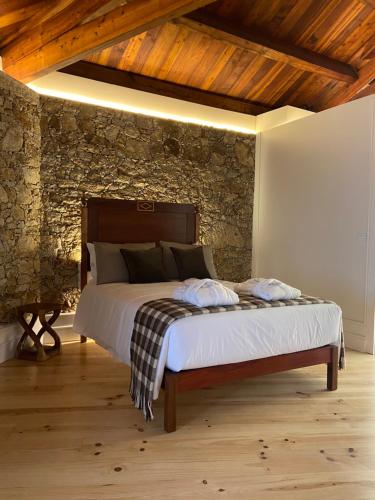 a bed in a room with a stone wall at Maia dos Reis Hotel Rural in Maia