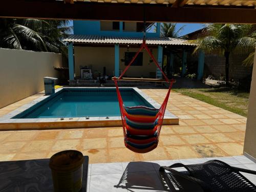 a red hammock hanging from a porch next to a pool at Casa de Veraneio in Caucaia