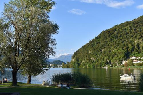 a boat on a lake with mountains in the background at Lago di Lugano - Casa Cecilia in Lavena Ponte Tresa