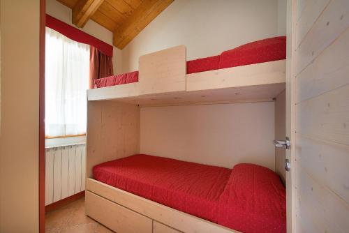 a bedroom with two bunk beds with red sheets at Residence Adamello Resort in Ponte di Legno