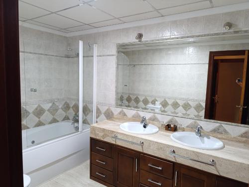 a bathroom with two sinks and a tub and a mirror at Hostal Jayma in Salobreña