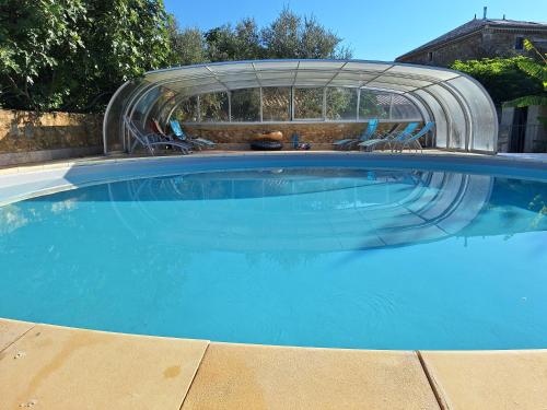 a large swimming pool with a slide in a yard at Gîte avec piscine couverte in Saint-Julien-de-Peyrolas
