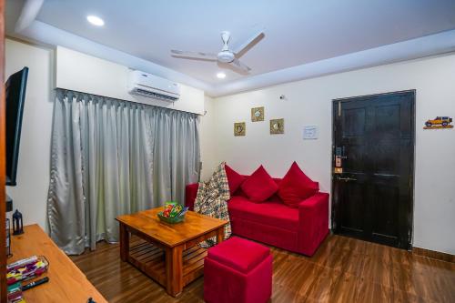 a living room with a red couch and a table at Skylight BnB F203 - 2BHK with pool near Candolim beach in Candolim