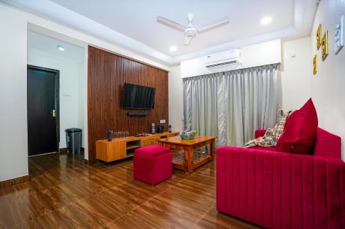 a living room with a red couch and a table at Skylight BnB F203 - 2BHK with pool near Candolim beach in Candolim