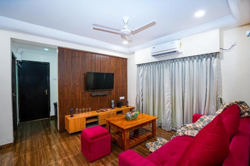 a living room with a red couch and a tv at Skylight BnB F203 - 2BHK with pool near Candolim beach in Candolim