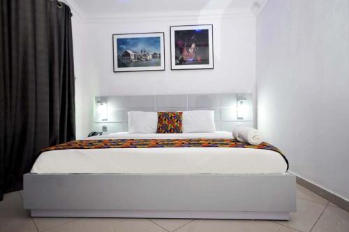 a bedroom with a large white bed with two pictures on the wall at Chakaville Beach Resort in Iberekodo
