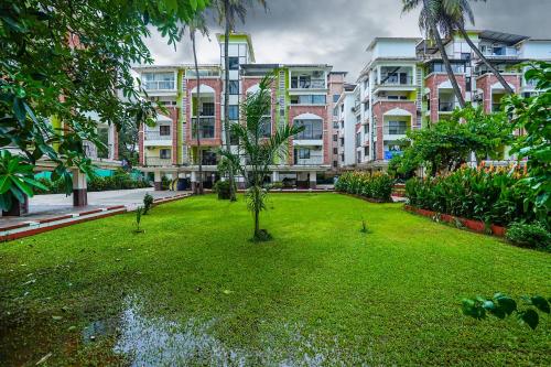 a green yard in front of a large building at Skylight BnB F203 - 2BHK with pool near Candolim beach in Candolim