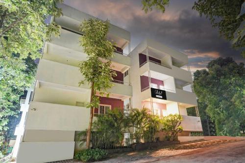 a white building with trees in front of it at Collection O Hebbal Mysore in Mysore