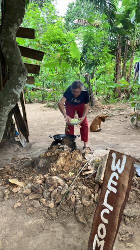 a man is preparing food in front of a fire at Organic Food Forest And Camp in Hohoe