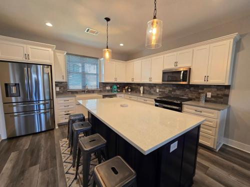 a kitchen with white cabinets and a kitchen island with stools at Modern Retreat in Sherman in Sherman