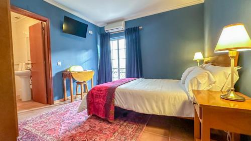 a bedroom with blue walls and a bed with a red rug at Poets Tavern & Inn in Avô