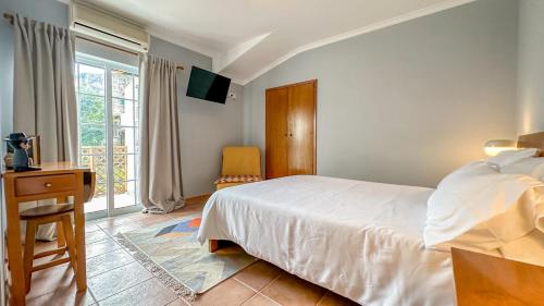 a bedroom with a bed and a desk and a window at Poets Tavern & Inn in Avô
