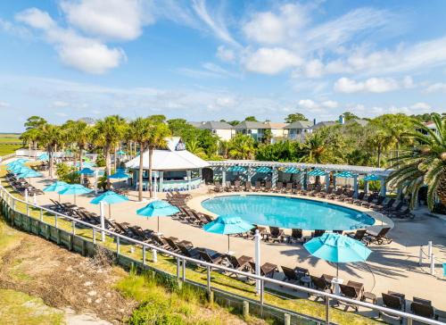 an image of a pool at a resort with blue umbrellas at Experience Modern Coastal Living in this Beautifully Designed 4-Bed, 4-Bath Home in Fripp Island