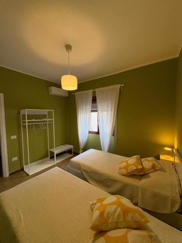 a green bedroom with two beds and a window at Una Rotonda sul Mare in Formia