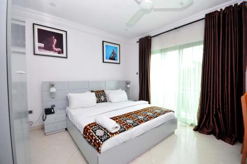 a white bedroom with a large bed and a window at Chakaville Beach Resort in Iberekodo