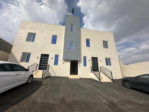 a large white building with blue shutters on it at شقة الريف الهادئة in Al Majma