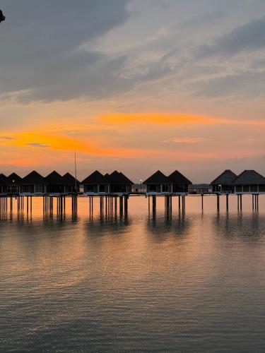 a group of huts on the water at sunset at Avani Sepang Goldcoast Resort in Tanjong Sepat