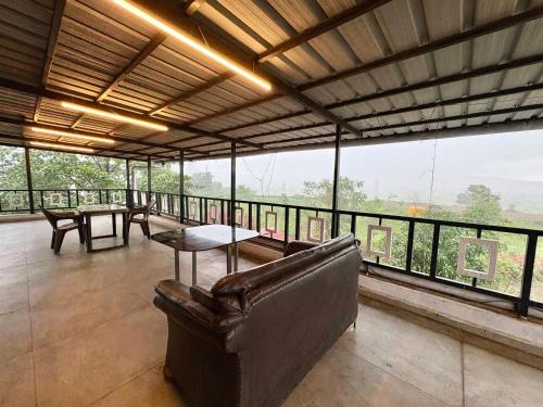 a living room with a couch and a table and windows at Zenstays Villa Igatpuri in Igatpuri