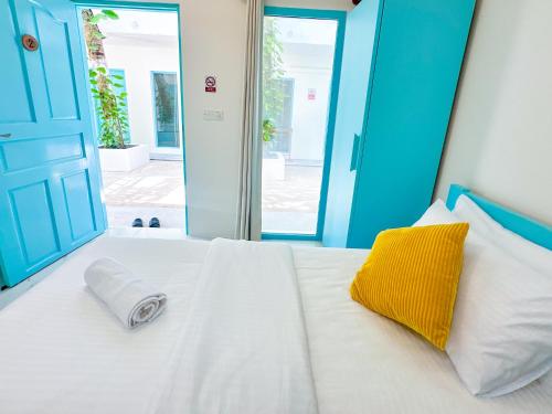 a bed with a yellow and white pillow on it at SunSeaSurf Maldives in Thulusdhoo