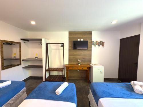 a hotel room with two beds and a desk at Pousada Gente Bonita João Fernandes in Búzios
