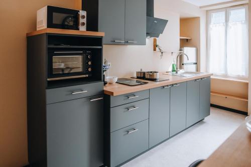 eine Küche mit grauen Schränken und einer Mikrowelle in der Unterkunft La Maison MMM - Proche Centre & Commerces in Châteauroux
