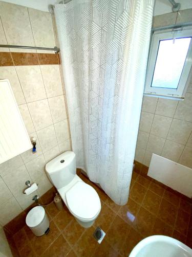 a bathroom with a toilet and a shower curtain at Vira Apartment in Pherrai