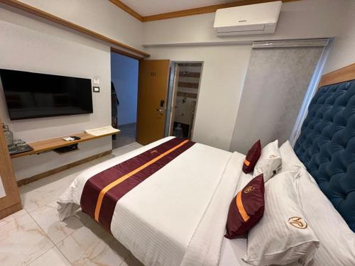 a bedroom with a large bed and a television at The VP Residency Towerrs in Tiruttani